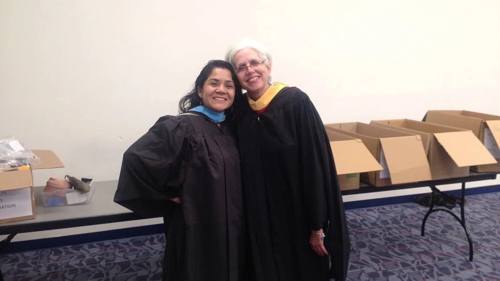 Paola Branda con toga de graduación junto a otra graduada